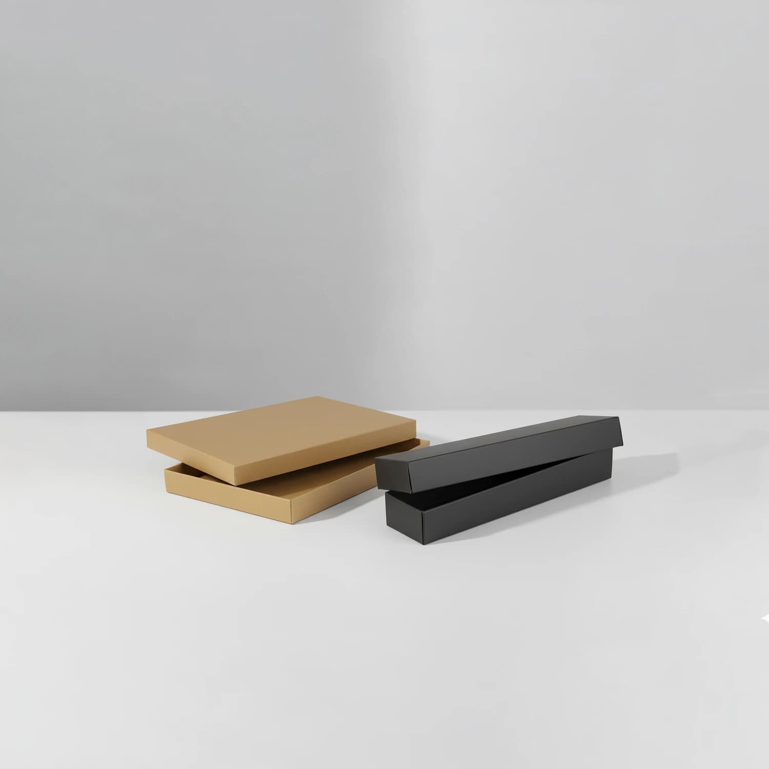 Two cardboard boxes with separate lids: one black, one kraft brown, on a neutral background