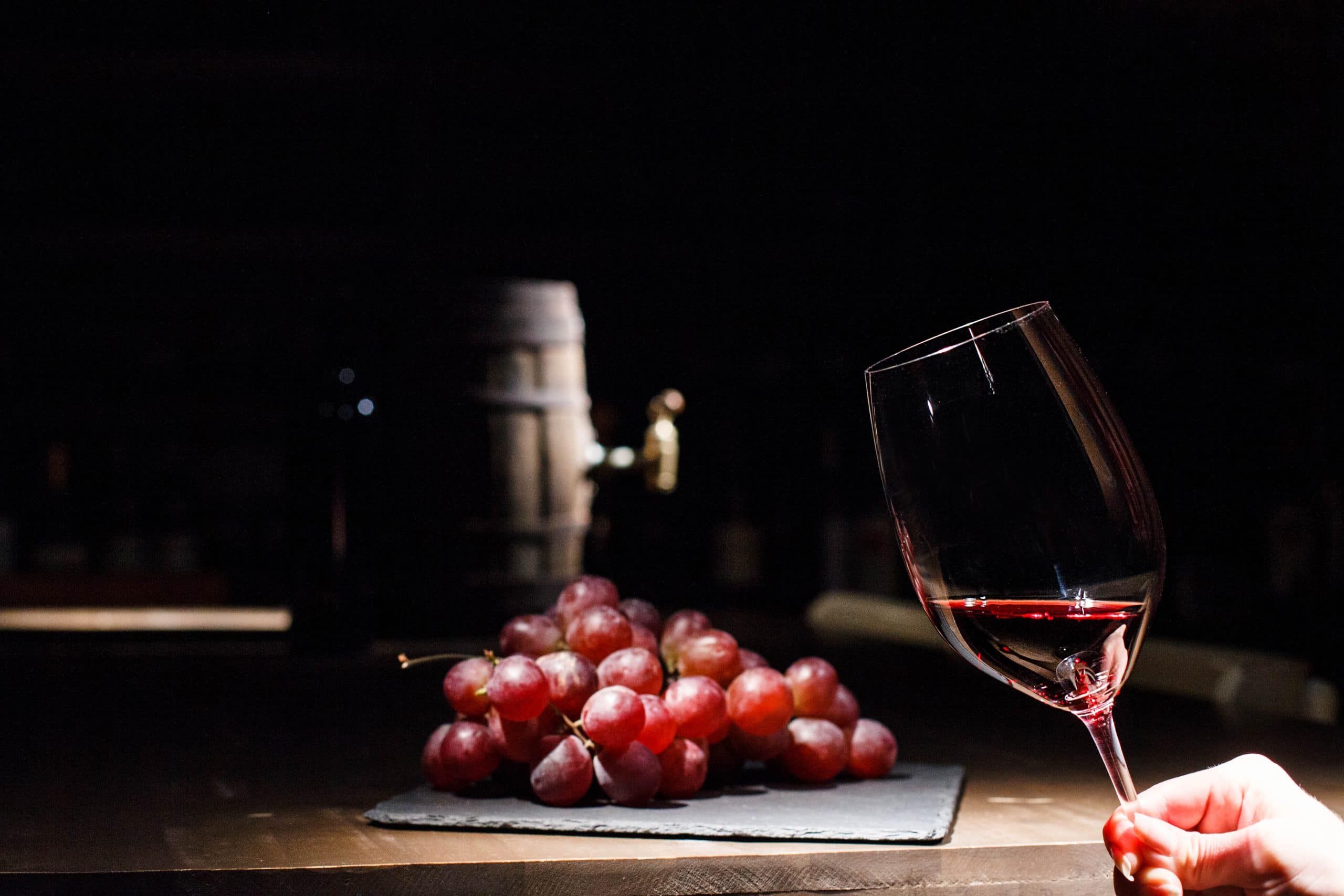 /wine-box-packaging/woman-holds-glass-wine-before-bunch-grape-lying-black-plate.jpg
